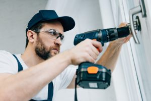 adult-repairman-in-goggles-fixing-window-handle-by-electric-drill.jpg